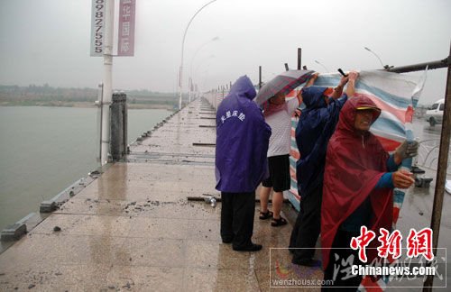 圖為大風吹垮的橋欄已被清理，工人們在冒雨加裝圍擋。