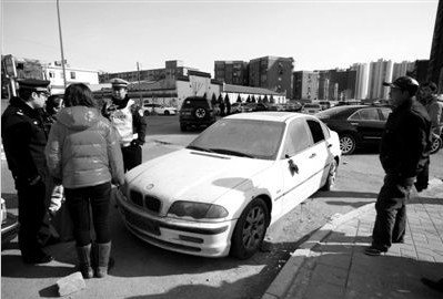 昨日，交警來到南湖西園南路西側路邊查看停放在路邊的寶馬車，該車停在此處已有兩年多。本報記者 孫純霞 攝