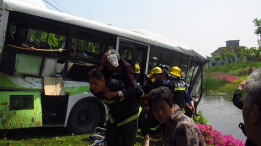 公交車被撞到幾十米外的河邊，車體前部受損嚴重。圖為接警后，消防人員很快來到現場，將乘客從車廂里逐個救出。