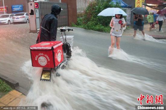 2012年7月21日，北京普降暴雨，朝陽區(qū)北部立水橋南地區(qū)積水嚴(yán)重。一小區(qū)門口，積水沿斜坡形成巨大水流，阻礙人們通行。圖片來源：CFP視覺中國(guó)