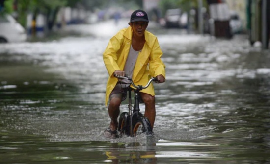 菲律賓暴雨，馬尼拉洪澇災(zāi)害，一名騎自行車的男子涉水穿過被洪水淹沒的街道。